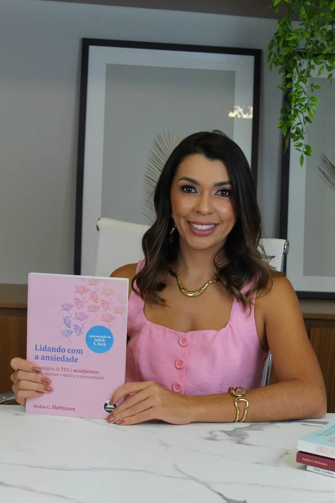 Karem Martins segurando o livro Lidando com a ansiedade, de Stefan G. Hofmann